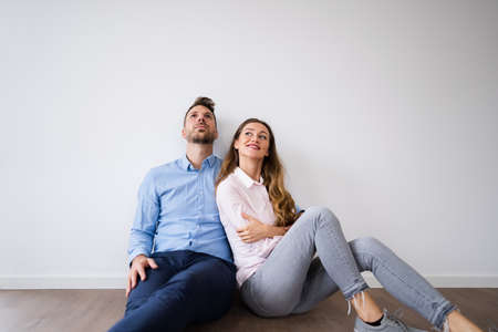 Young Happy Couple Thinking And Dreaming In New Houseの写真素材