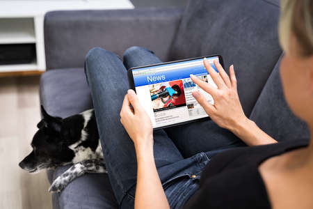 Reading Online Newspaper On Tablet. Watching News On Websiteの写真素材