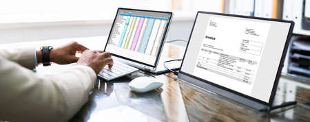 Looking At Invoice And Spreadsheet On Laptop At Workの写真素材