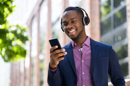 African American Man Listening Music On Wireless Headphones Outsideの写真素材