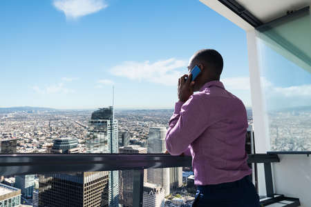 African Man Looking At City Downtown On A Balcony