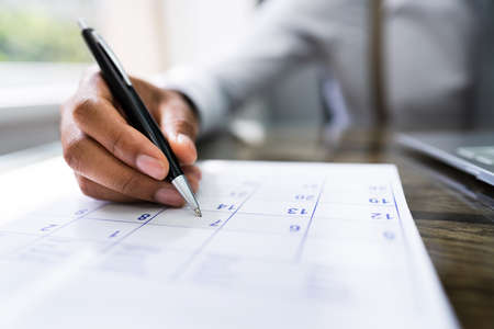 Calendar Deadline. Young Man Holding Pen Marking Date