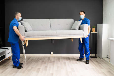 Professional Movers Moving Couch Furniture In Face Maskの写真素材