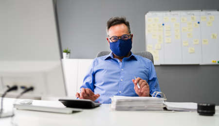 Elder Business Employee Working At Computer Wearing Facial Maskの写真素材