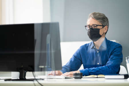 Employee In Office Social Distancing Using Sneeze Guard And Face Mask