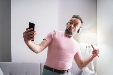 Smiling Older Senior Listening Music On Headphonesの写真素材