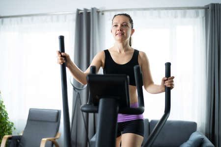 Woman Training On Elliptical Trainer At Home