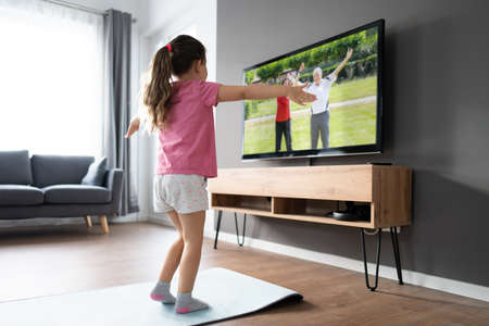 Kid Doing Online TV Fitness Exercise At Homeの写真素材
