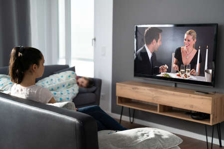 Woman Watching TV At Sofa While Child Is Sleepingの写真素材