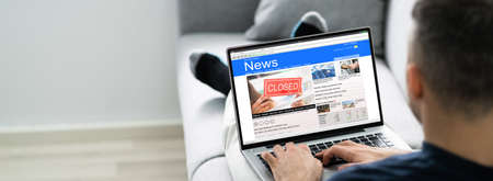 Man Using Computer Reading Electronic News Articlesの写真素材