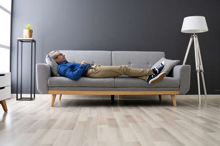 Senior Man Relaxing On Sofa In Living Roomの写真素材