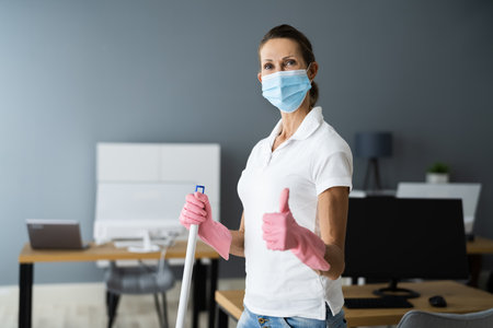 Female Janitor Mopping Floor In Face Mask In Office