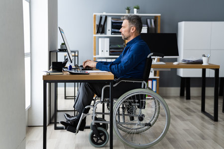 Disabled Handicapped Man In Wheelchair Working Using Computer Technologyの写真素材