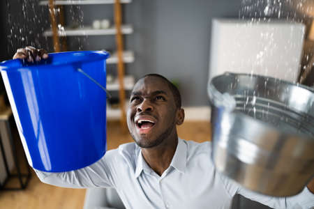 Leaking Water From Ceiling In Apartment. Holding Bucket