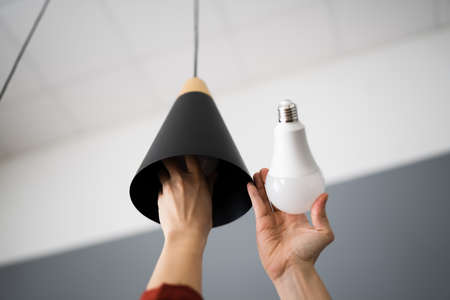 Woman Changing Broken Light Bulb To LEDの写真素材