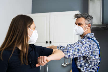 Woman Elbow Bump With Repair Man Or Handyman In Face Mask