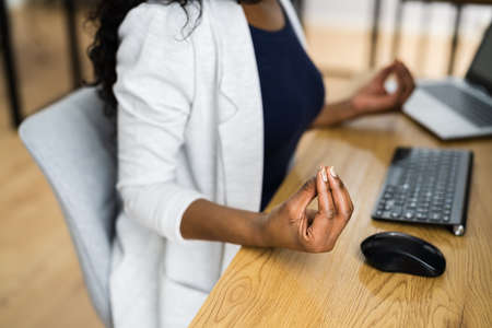 Office Employee Doing Mental Exercise And Yoga At Tableの写真素材