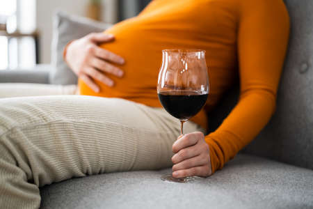 Pregnant Woman Holding Wine Near Belly Stomachの写真素材