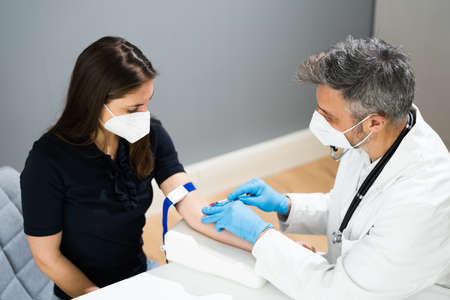 Blood Draw By Doctor In Laboratory In Face Maskの写真素材