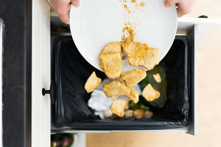 Throwing Away Leftover Food In Trash Or Garbage Dustbin