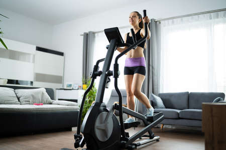 Woman Training On Elliptical Trainer At Home