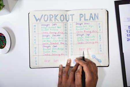 An Elevated View Of A Person Making Note Of Workout Plan On Notebookの写真素材