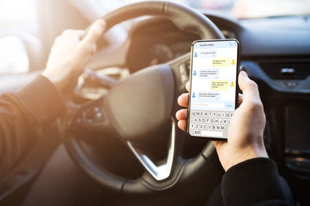 Man Typing Text Message On Mobile Phone While Driving Carの写真素材
