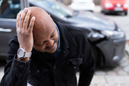 Car Accident And Injury. Damaged Auto And African Manの写真素材