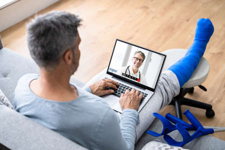 Video Conference Call With Doctor. Man With Broken Injured Leg