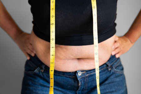 Caucasian Woman With Belly Fat Using Tape Measure Closeup