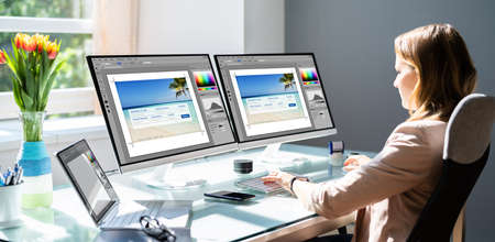 Woman Working On Computer Monitors Making Graphic Web Designの写真素材
