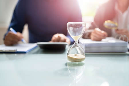 Hourglass And Time Crunch With Document In Officeの写真素材