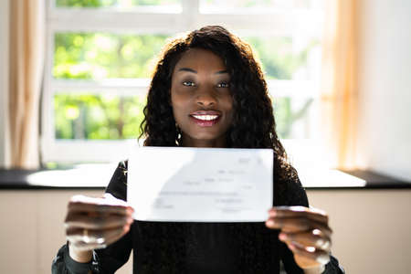 Black Business Woman Holding Pay Check Or Paycheckの写真素材