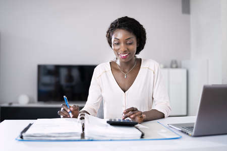 Happy Young African Woman Doing Taxes And Money Budgetの写真素材