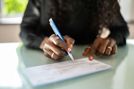 African Woman Writing Check. Payroll Salary Chequeの写真素材
