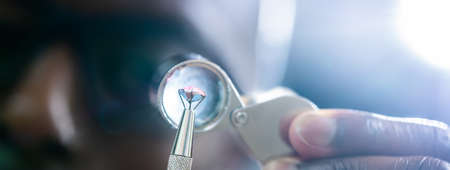African American Jeweler Holding Diamond And Using Loupe Glass