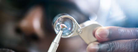 African American Jeweler Holding Diamond And Using Loupe Glassの写真素材