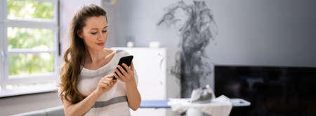 Ironing Laundry. Women Distracted With Mobile Phone