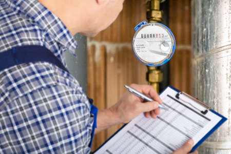 Technician With Clipboard Reading Water Meter Or Counterの写真素材