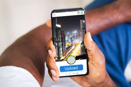 African American Man Uploading Mobile Phone Photo Onlineの写真素材
