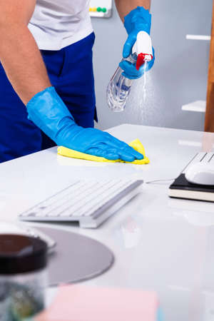 Office Cleaning Service. Janitor Spraying Desk. Workplace Hygieneの写真素材