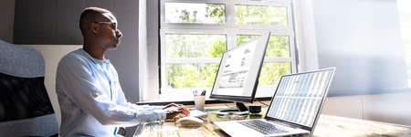 African American Tax Accountant Checking Invoice On Office Computerの写真素材
