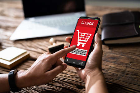 Woman's Hand Holding Mobile Phone With Shopping Coupon