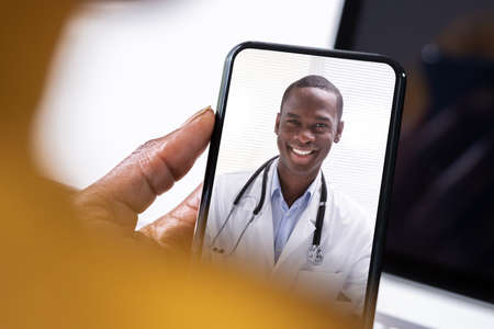 Female In Telemedicine Video Conference With Doctor On Mobile Phoneの写真素材
