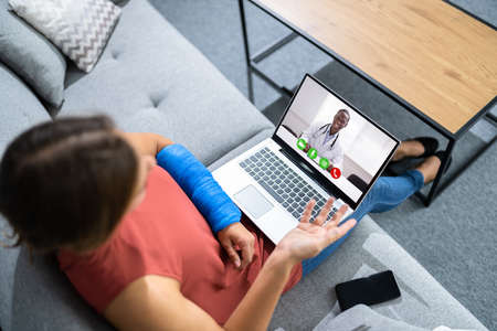 Video Chat With Doctor On Laptop. Injured Broken Arm