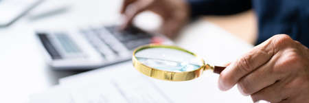 Auditor Using Magnifying Glass For Audit And Fraud Investigation
