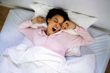 Yawning African American Woman Sleeping In Bed