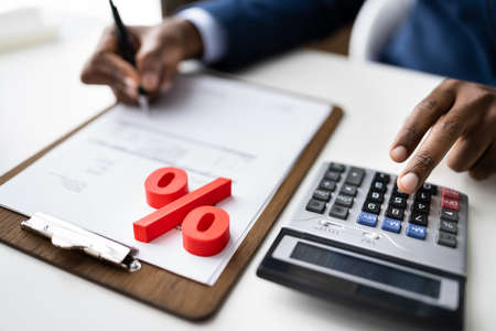 Red Percentage Symbol In Front Of Businessperson Calculating Invoiceの写真素材