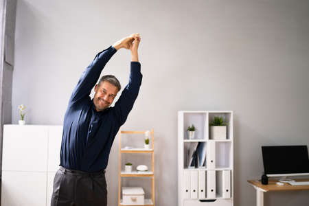 Arms Stretch Exercise Standing Near Desk In Office