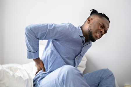 Man Suffering From Back Pain Sitting On Bedの写真素材
